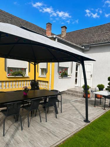 a patio with a table and chairs under an umbrella at Viktor Apartmanház in Zamárdi