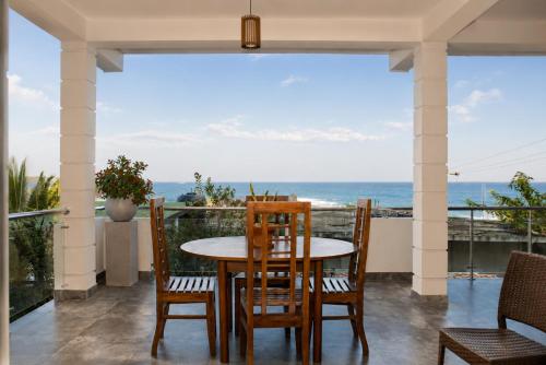 a dining room with a table and chairs and the ocean at Queens Beach Hotel in Tangalle