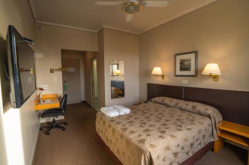 a hotel room with a bed and a desk at Comodoro Hotel in Comodoro Rivadavia