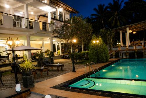 a pool in front of a hotel at night at Queens Beach Hotel in Tangalle