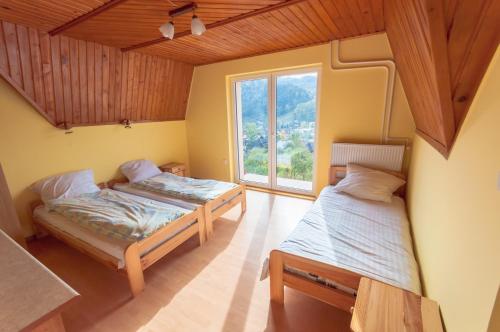 two beds in a room with a window at Porębówka in Szczawnica
