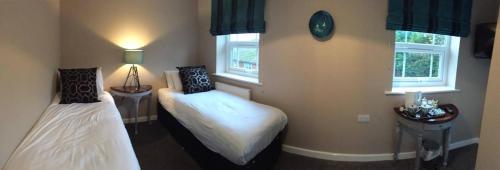 a bedroom with two beds and two windows at The Anchor Inn in Sutton Bridge