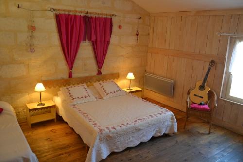 Un dormitorio con una cama y una guitarra. en Mas De Sylvereal en Sylvéréal