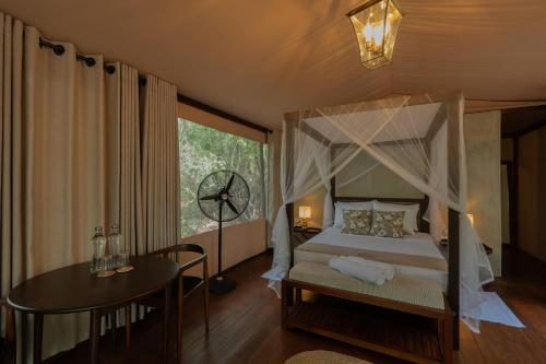 a bedroom with a canopy bed and a table at Chena Wilds Wilpattu in Horuwila