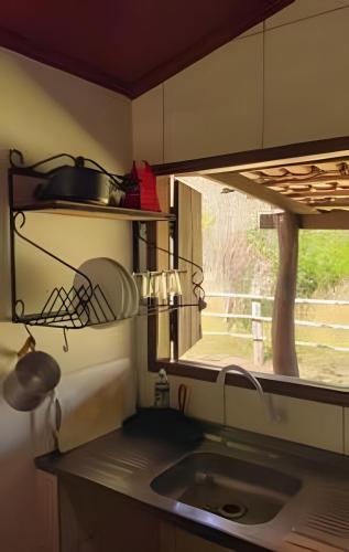 a kitchen counter with a sink and a window at Chalé Prainha com Cozinha - Valle das Pedras in Sao Jorge