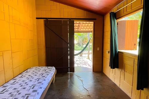 a small room with a bed and a door at Chalé Prainha com Cozinha - Valle das Pedras in Sao Jorge