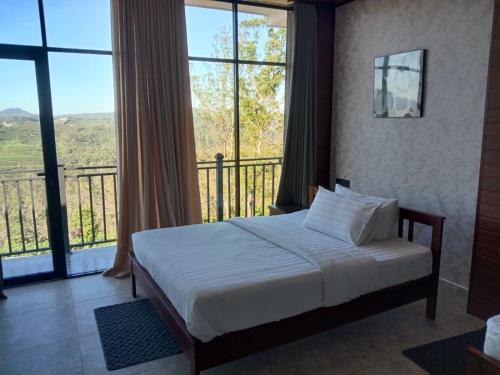 a bedroom with a bed and a balcony with windows at Falcon View in Nuwara Eliya