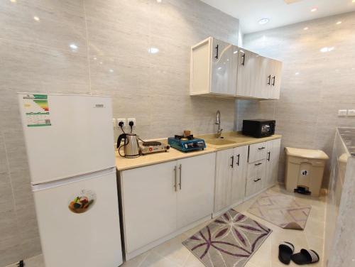 a kitchen with white cabinets and a white refrigerator at شقق ضوء القمر Moonlight Apartment in Rahwat al Barr