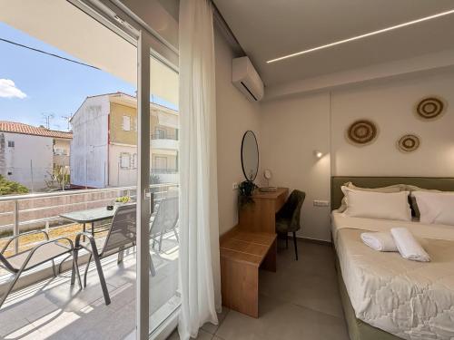 a bedroom with a bed and a balcony with a table at Blue Tree Suites in Pefkochori