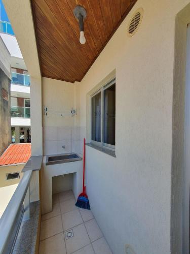 a bathroom with a mop and a sink and a window at Pousada Acapulco in Bombinhas
