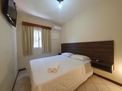 a bedroom with a bed with two towels on it at Pousada Acapulco in Bombinhas