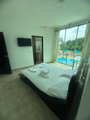 a bedroom with a bed with a view of a pool at Hotel Cristalina in Melgar