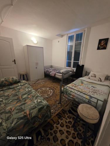 a room with two beds and a chair and a window at PR001 3 chambres in Le Blanc-Mesnil