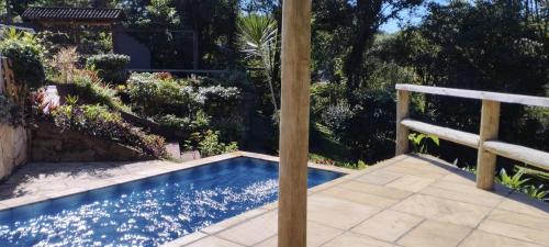 a swimming pool in a garden with a fence at Tiny House II - experiência de refúgio exclusivo in Gravataí