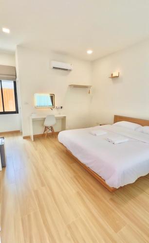 a bedroom with a large white bed and a desk at Minimo Hotel - โรงแรมมินิโม กุมภวาปี in Amphoe Kumphawapi