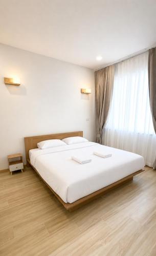 a bedroom with a large white bed and a window at Minimo Hotel - โรงแรมมินิโม กุมภวาปี in Amphoe Kumphawapi