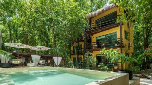 a swimming pool in front of a house with trees at Terasu Riviera Maya Hotel & Spa, en Xcaret in Playa del Carmen