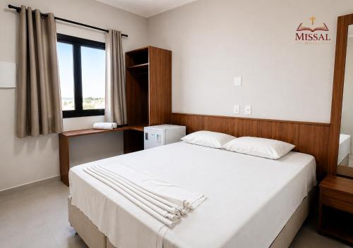 ein Schlafzimmer mit einem großen weißen Bett und einem Fenster in der Unterkunft Missal Hotel in Aparecida