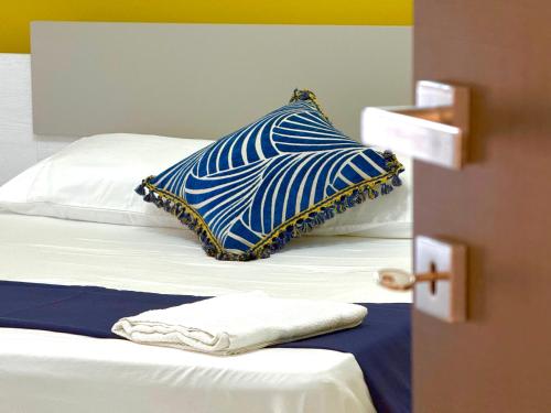 a bed with a blue and white pillow on it at Taormina Naxos Home 2 in Giardini Naxos