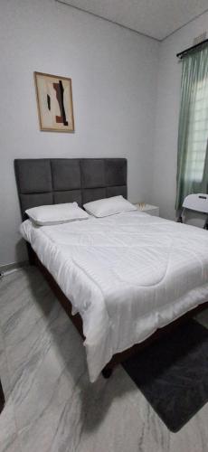 a bedroom with a large bed with white sheets at Lynch Apartments 2 - Mimosa Chilanga in Lusaka