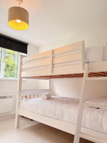 a white bunk bed in a white room at 105 beach lodge millendreath in Looe