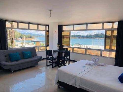 a bedroom with a bed and a couch and windows at Apartahotel El Horizonte in Guatapé