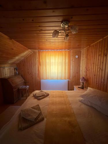 a bedroom with a large bed in a wooden room at Casa de Vacanță Haneș - Private Cabin - Orchard & Mountain Views - Transalpina & viaTransilvanica in Pianu de Sus