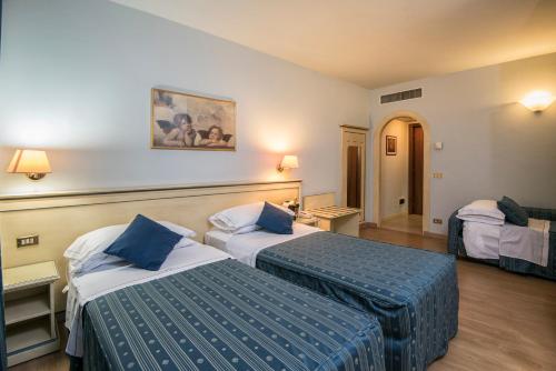 a hotel room with two beds with blue pillows at Marchi Hotel in Soliera