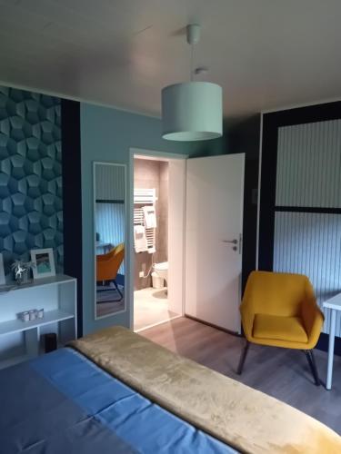a bedroom with a bed and a yellow chair at Chez Martine et Jean-Marc in Tintigny