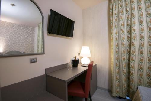 a room with a desk with a lamp and a mirror at Marchi Hotel in Soliera