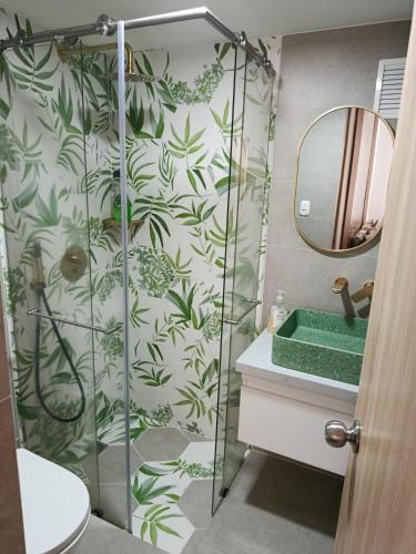 a bathroom with a shower with green leaves on the wall at Apartaestudio vacacional in Armenia
