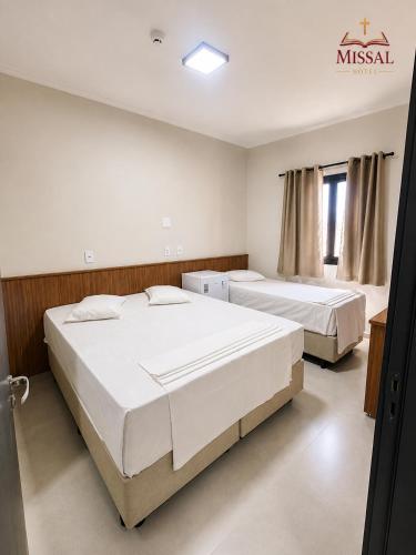 ein Schlafzimmer mit zwei Betten und einem Schild an der Wand in der Unterkunft Missal Hotel in Aparecida