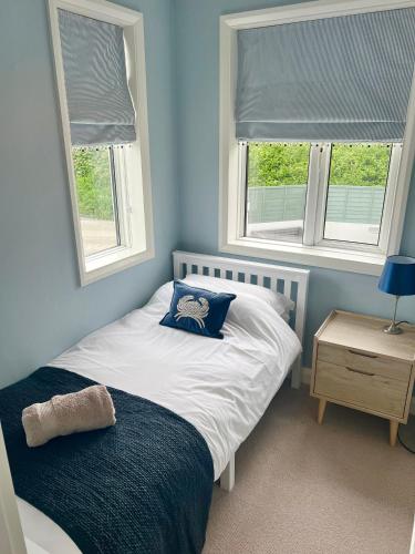 a small bedroom with a bed and two windows at The Cornish Retreat in Bude