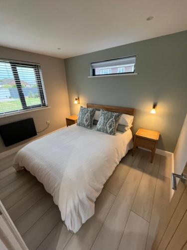 a bedroom with a large white bed with two pillows at Riverside Lodge in Creech Saint Michael