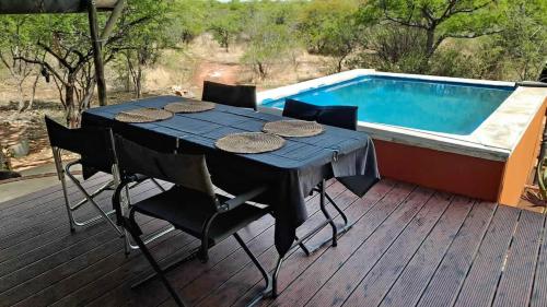 a table and chairs on a deck next to a swimming pool at Zuri Camp - Tent Kiama in Tsumeb