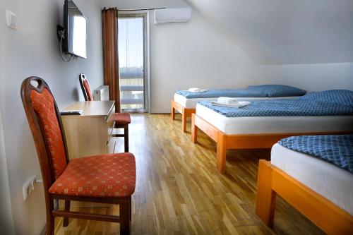 a room with three beds and a desk and a chair at Anna Vendégház Szeleste in Szeleste