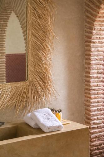 a bathroom with a sink with a mirror and towels at Riad Jawad & Spa in Marrakesh