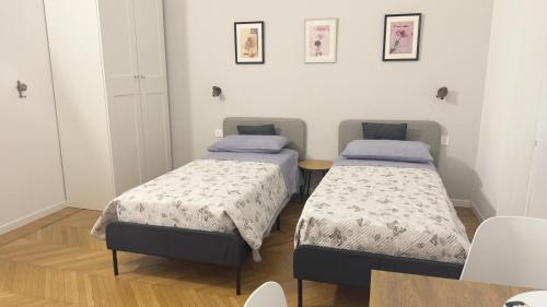 two beds in a small room with a table at Casa Dante 4 in Pavia