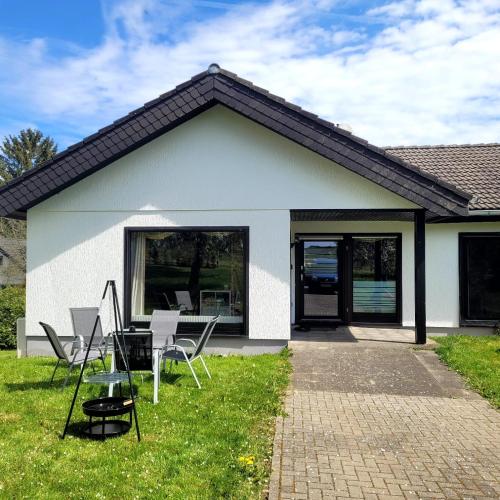 a white house with chairs on the grass at Familiennest-Eifel in Blankenheim