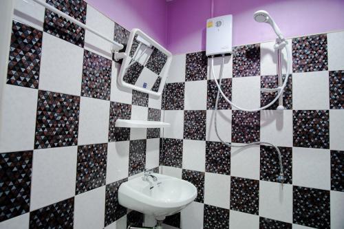 y baño con lavabo y paredes de azulejos blancos y negros. en Sweet Dreams Hometel, en Krabi