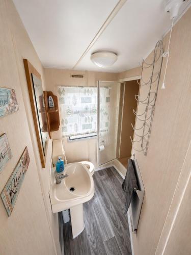 a small bathroom with a sink and a shower at The Hemsbee Static caravan 117 Sandsgate Hemsby in Hemsby