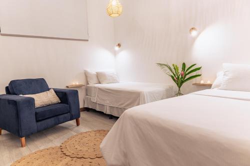 a bedroom with two beds and a blue chair at Samaya Wellness Lodge in Flores