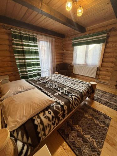 a bedroom with a large bed in a log cabin at Gostynnyi Dvir u Marichky in Lazeshchyna