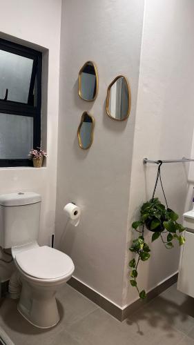 a bathroom with a toilet and three mirrors on the wall at The F402 Residence in Gaborone