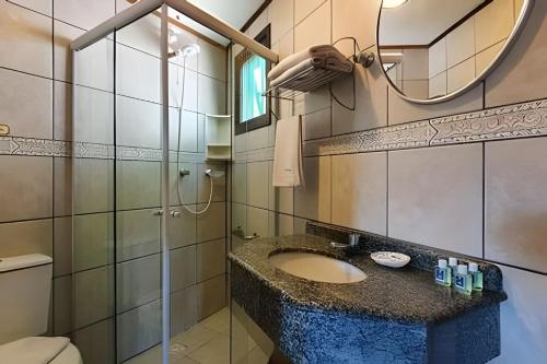 a bathroom with a sink and a toilet and a mirror at Villa Garoupeta in Bombinhas