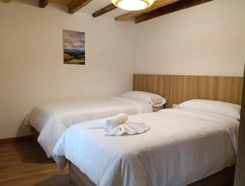 two beds with a towel on top of them in a room at ALOJAMIENTO MONTE EDILLA Naturaleza, Confort y Recarga Eléctrica in Quintana de los Prados