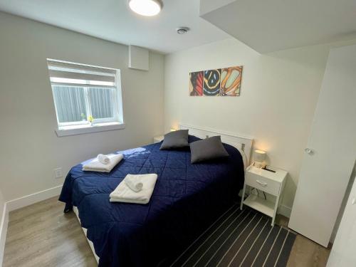 a bedroom with a blue bed with towels on it at Executive 2 Bedroom Garden Suite Free Parking - Save on Long Stays! in New Westminster