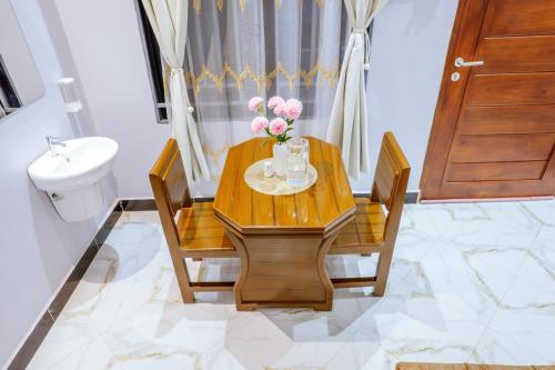a dining room table with a vase of flowers on it at Cozycore Apartment in Dodoma