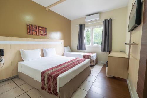 a hotel room with two beds and a television at Nobile Hotel Belém in Belém