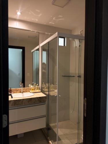 a bathroom with a glass shower and a sink at Heron Marinho Comfort Flat in Campina Grande